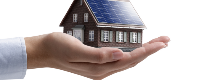 Hand holding a miniature house with solar panels, showcasing Go Local Powur’s dedication to sustainable, community-driven solar energy solutions.